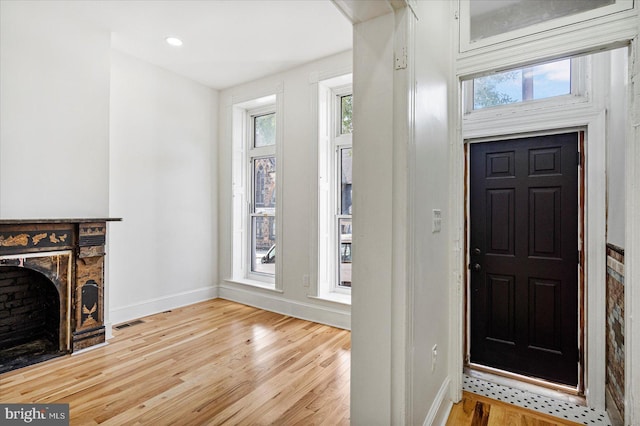 1630 E Biddle St, Baltimore, MD 21213 - foyer entrance featuring baseboards, light wood-style floors, and a fireplace