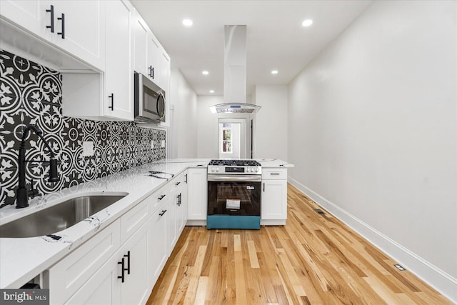 1630 E Biddle St, Baltimore, MD 21213 - kitchen with appliances with stainless steel finishes, island range hood, tasteful backsplash, white cabinetry, and light wood finished floors