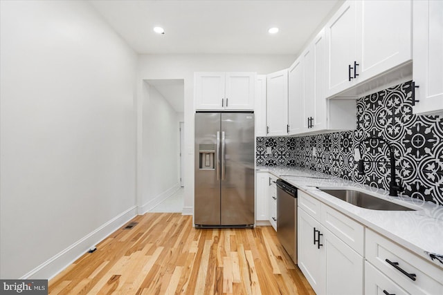 1630 E Biddle St, Baltimore, MD 21213 - kitchen with stainless steel appliances, backsplash, white cabinets, light wood-type flooring, and a sink