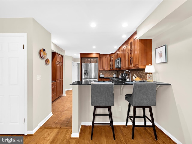 2772 Gingerview Ln, Annapolis, MD 21401 - kitchen with stainless steel appliances, a peninsula, dark countertops, decorative backsplash, and a breakfast bar