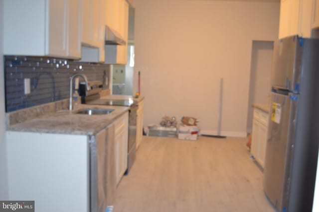 3111 E Baltimore St, Baltimore, MD 21224 - kitchen featuring freestanding refrigerator, a sink, decorative backsplash, light wood finished floors, and white cabinetry