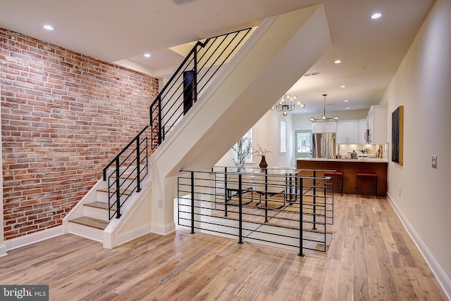 4938 Walton Ave, Philadelphia, PA 19143 - stairway featuring a chandelier, wood finished floors, brick wall, and recessed lighting