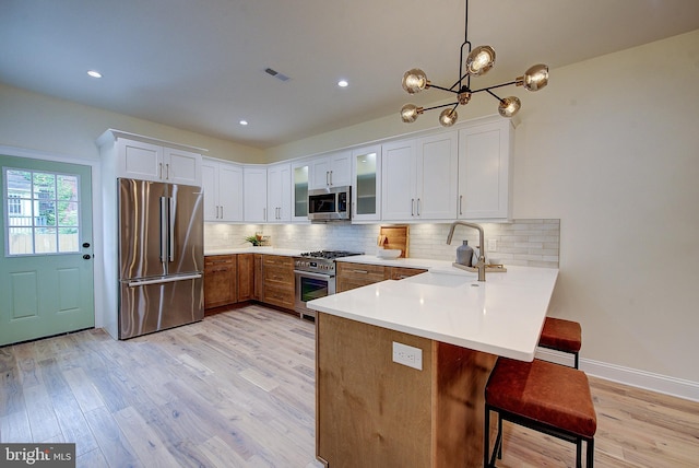 4938 Walton Ave, Philadelphia, PA 19143 - kitchen with appliances with stainless steel finishes, a peninsula, light wood-style flooring, light countertops, and recessed lighting