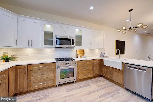 4938 Walton Ave, Philadelphia, PA 19143 - kitchen featuring stainless steel appliances, white cabinets, decorative light fixtures, tasteful backsplash, and a chandelier