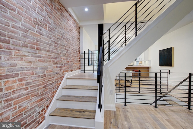 4938 Walton Ave, Philadelphia, PA 19143 - stairway featuring brick wall, wood finished floors, and recessed lighting