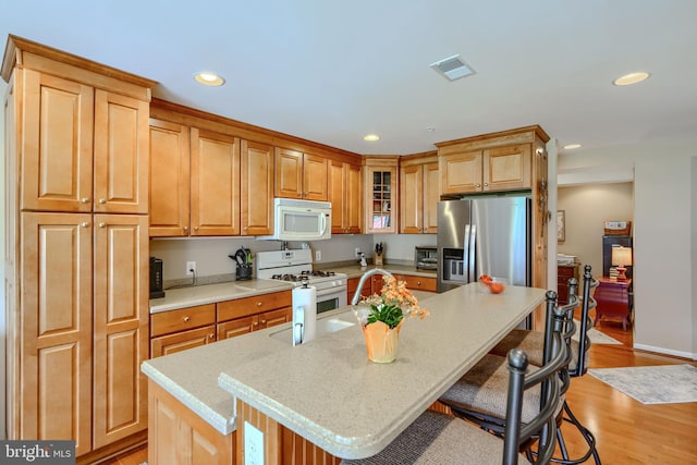 12251 Roundwood Rd Unit 301, Lutherville Timonium, MD 21093 - kitchen with white appliances, a kitchen breakfast bar, recessed lighting, light wood-type flooring, and glass insert cabinets
