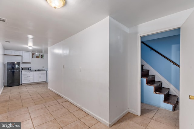 3826 W Bay Ave, Baltimore, MD 21225 - kitchen featuring freestanding refrigerator, stainless steel microwave, light tile patterned flooring, white cabinets, and baseboards