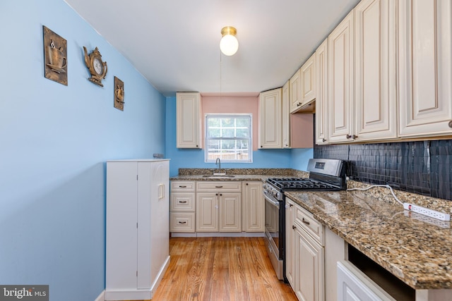 3826 W Bay Ave, Baltimore, MD 21225 - kitchen with gas range, a sink, light wood-style floors, decorative backsplash, and stone countertops