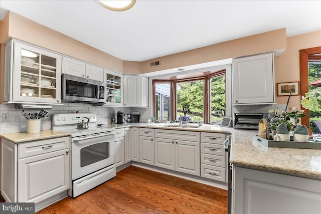 1771 Hunters Cir, West Chester, PA 19380 - kitchen featuring electric range, stainless steel microwave, a sink, decorative backsplash, and wood finished floors