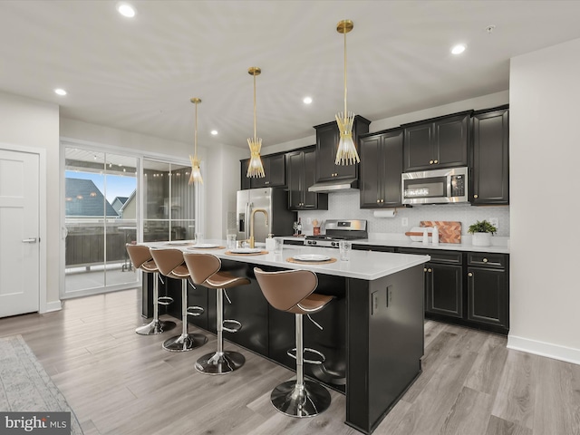 7330 Isabella Rd, Laurel, MD 20723 - kitchen featuring stainless steel appliances, a kitchen island with sink, light countertops, light wood finished floors, and dark cabinetry