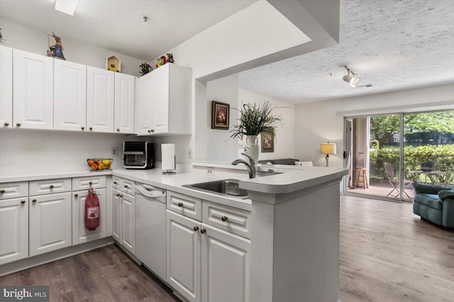 20273 Beechwood Ter Unit 103, Ashburn, VA 20147 - kitchen with white dishwasher, a sink, a textured ceiling, a peninsula, and white cabinets