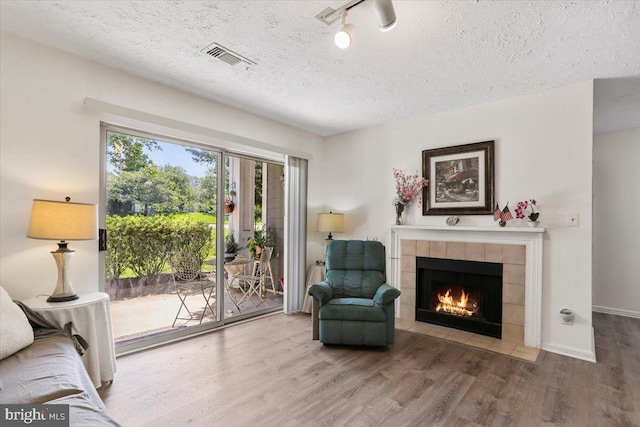20273 Beechwood Ter Unit 103, Ashburn, VA 20147 - living area featuring wood finished floors, a tile fireplace, a textured ceiling, and baseboards