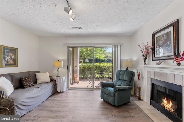 20273 Beechwood Ter Unit 103, Ashburn, VA 20147 - living area with a tile fireplace, wood finished floors, rail lighting, and a textured ceiling