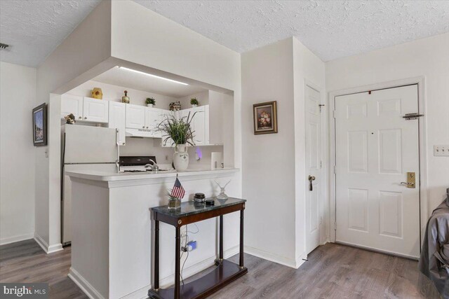 20273 Beechwood Ter Unit 103, Ashburn, VA 20147 - kitchen featuring freestanding refrigerator, dark wood-style flooring, under cabinet range hood, a textured ceiling, and a peninsula