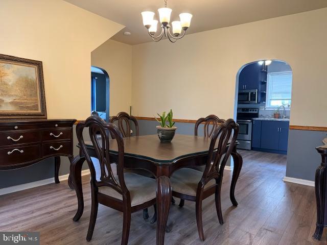 2329 Canby St, Harrisburg, PA 17103 - dining space with a chandelier, arched walkways, wood finished floors, and baseboards