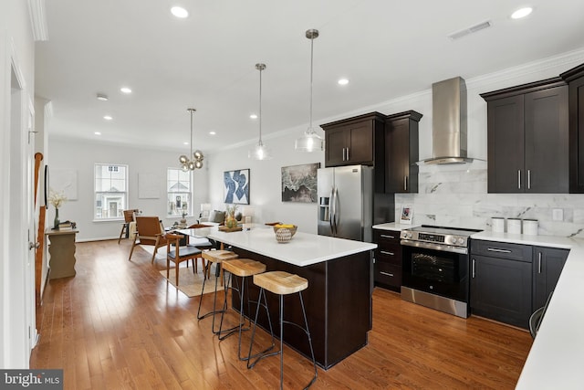 402 Woodcrest Dr SE, Washington, DC 20032 - kitchen featuring stainless steel appliances, wall chimney exhaust hood, light countertops, decorative backsplash, and ornamental molding
