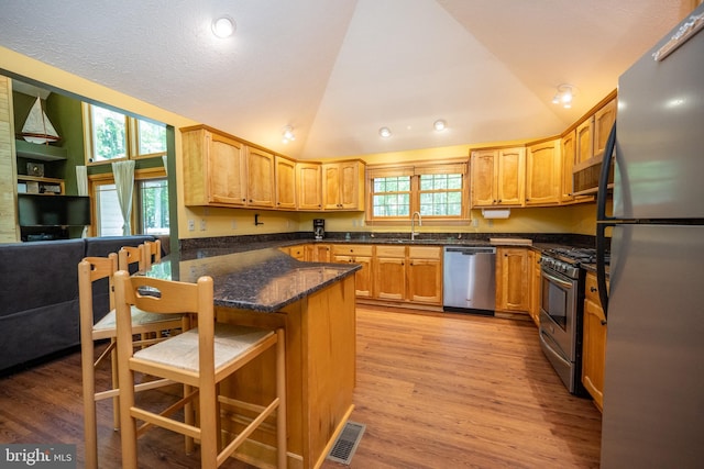 793 Mountainview Dr, Oakland, MD 21550 - kitchen featuring appliances with stainless steel finishes, lofted ceiling, a kitchen breakfast bar, light wood finished floors, and dark stone counters