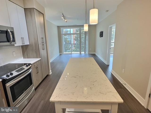 145 Riverhaven Dr Unit 254, Oxon Hill, MD 20745 - kitchen featuring appliances with stainless steel finishes, a center island, dark wood-style flooring, tasteful backsplash, and hanging light fixtures