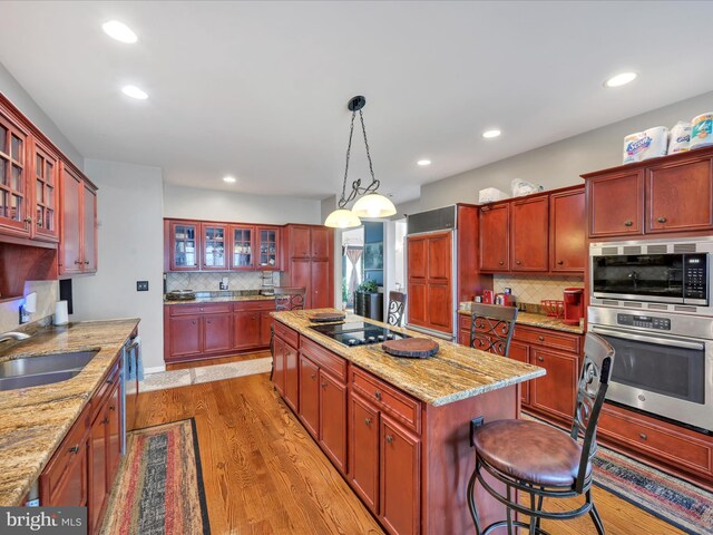 3002 Ridgeview Dr, Orwigsburg, PA 17961 - kitchen featuring a sink, black electric cooktop, a center island, tasteful backsplash, and light wood-type flooring