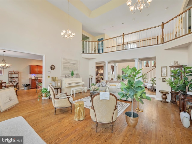 3002 Ridgeview Dr, Orwigsburg, PA 17961 - living room with a chandelier, a towering ceiling, light wood-type flooring, and ornate columns