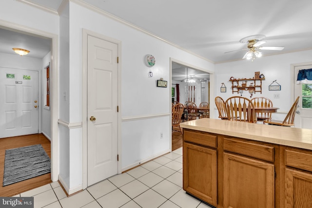 38390 Golden Beach Rd, Mechanicsville, MD 20659 - kitchen with crown molding, ceiling fan, light countertops, light tile patterned floors, and brown cabinetry