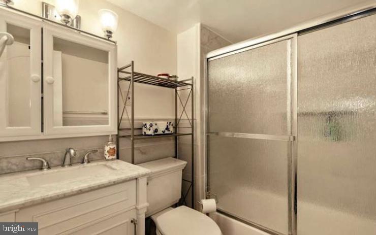 9820 Georgia Ave Unit 21-301, Silver Spring, MD 20902 - bathroom featuring vanity, toilet, and shower / bath combination with glass door