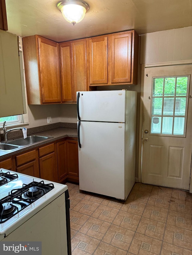 3602 Tulip Ave, Baltimore, MD 21227 - kitchen featuring white appliances, a sink, brown cabinetry, and dark countertops