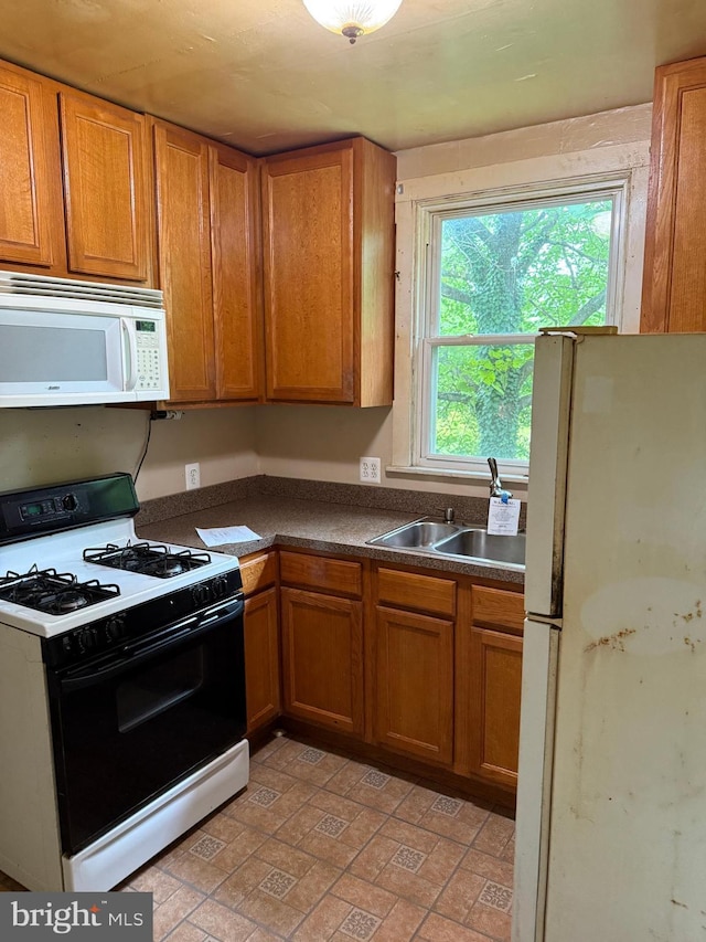 3602 Tulip Ave, Baltimore, MD 21227 - kitchen featuring white appliances, a sink, dark countertops, and brown cabinetry