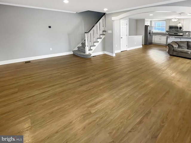 1507 E Duval St, Philadelphia, PA 19138 - unfurnished living room with arched walkways, baseboards, crown molding, wood finished floors, and stairway