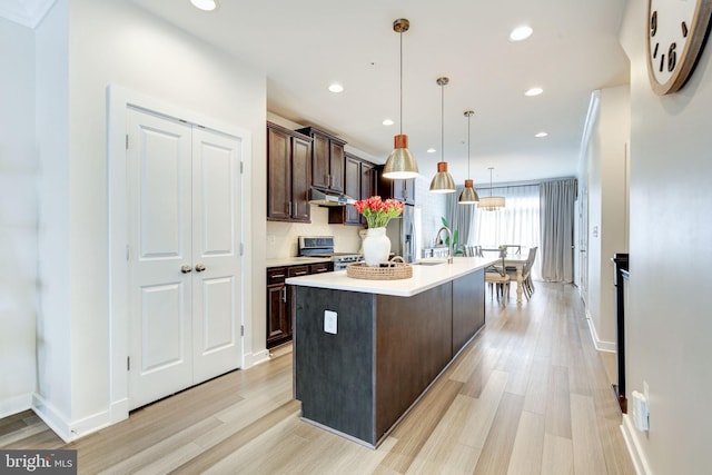 3409 Stone Barn Dr, Frederick, MD 21704 - kitchen with appliances with stainless steel finishes, under cabinet range hood, dark brown cabinets, light countertops, and light wood-style floors