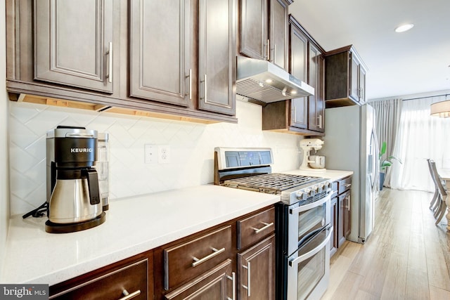 3409 Stone Barn Dr, Frederick, MD 21704 - kitchen with range with two ovens, under cabinet range hood, dark brown cabinetry, light countertops, and recessed lighting
