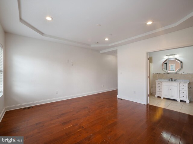 1705 E Chase St, Baltimore, MD 21213 - unfurnished living room with light wood-style flooring, a tray ceiling, recessed lighting, and baseboards