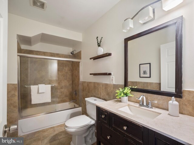 1705 E Chase St, Baltimore, MD 21213 - bathroom featuring vanity, tile walls, toilet, combined bath / shower with glass door, and tile patterned floors