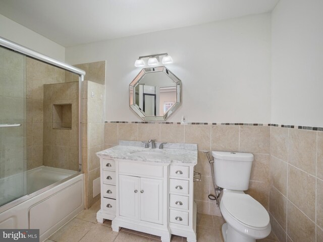 1705 E Chase St, Baltimore, MD 21213 - bathroom featuring vanity, toilet, tile walls, shower / bath combination with glass door, and tile patterned flooring
