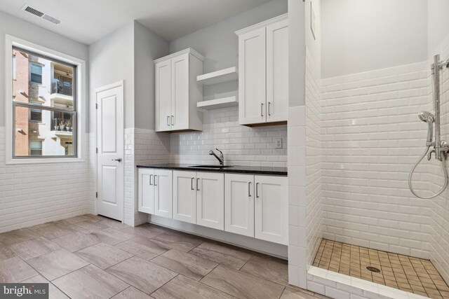 23630 Havelock Walk Ter Unit 205, Ashburn, VA 20148 - kitchen featuring open shelves, dark countertops, white cabinets, a sink, and wainscoting