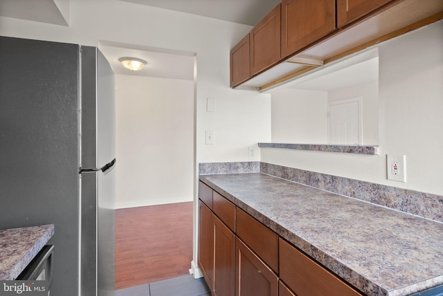 713 Brandywine St SE Unit 303, Washington, DC 20032 - kitchen with freestanding refrigerator, brown cabinetry, wood finished floors, and baseboards