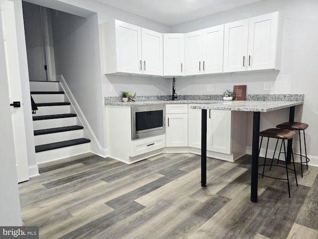 1612 Lemontree Ln, Silver Spring, MD 20904 - kitchen with built in microwave, baseboards, white cabinetry, light wood-type flooring, and light stone countertops