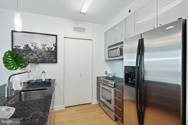 2101 Market St Unit 3605, Philadelphia, PA 19103 - kitchen featuring stainless steel appliances, a sink, light wood-style floors, dark stone counters, and pendant lighting