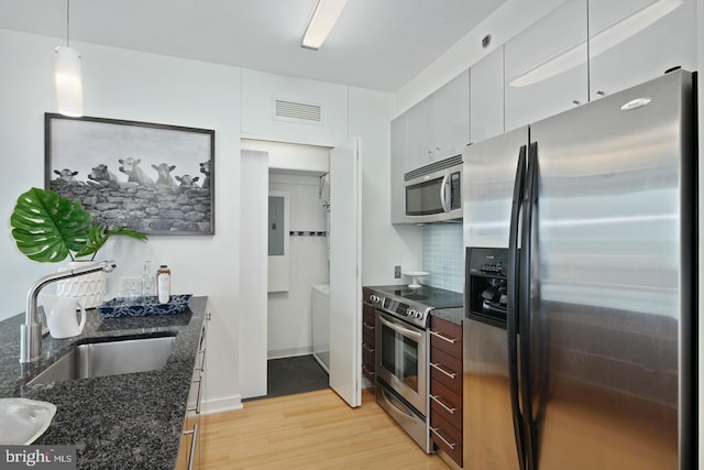 2101 Market St Unit 3605, Philadelphia, PA 19103 - kitchen with stainless steel appliances, a sink, light wood-style floors, backsplash, and dark stone counters