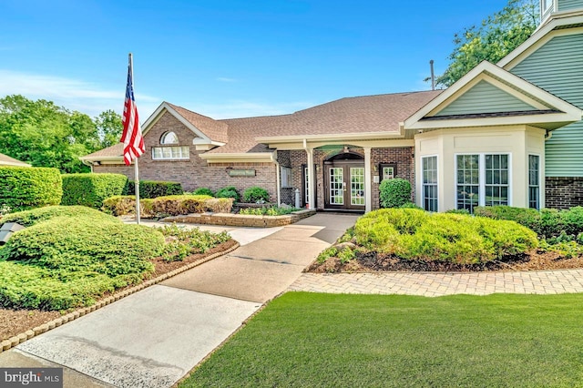 7011 Elm Ct, Monmouth Junction, NJ 08852 - view of front of house with french doors, brick siding, roof with shingles, and a front lawn