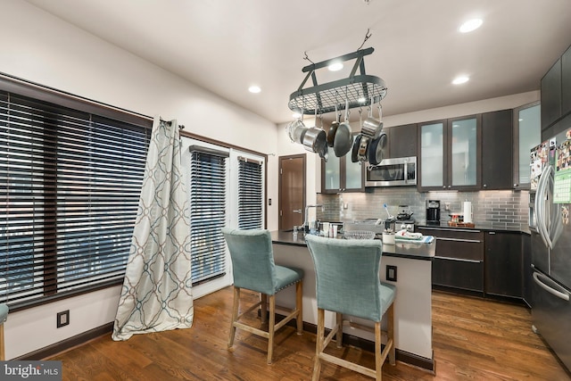 8861 Ashgrove House Ln, Vienna, VA 22182 - kitchen with stainless steel appliances, backsplash, a breakfast bar, dark countertops, and glass insert cabinets