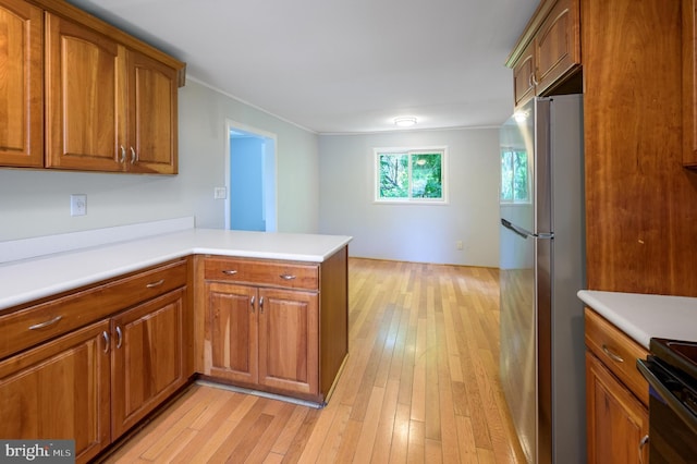 624 Hunt Ave, Trenton, NJ 08610 - kitchen featuring freestanding refrigerator, brown cabinets, light wood-type flooring, a peninsula, and range