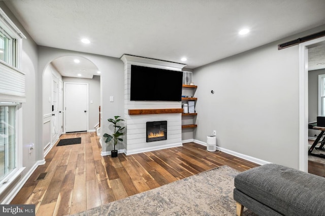 11636 Doxdam Ter, Germantown, MD 20876 - living area featuring arched walkways, wood-type flooring, baseboards, a large fireplace, and recessed lighting