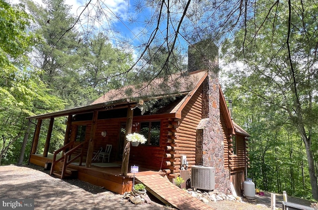 11882 Bumbarger Cir, Petersburg, PA 16669 - view of front facade featuring log exterior, central AC, a chimney, and covered porch