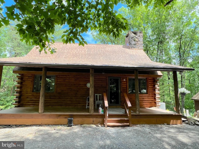 11882 Bumbarger Cir, Petersburg, PA 16669 - cabin featuring log siding, covered porch, a chimney, and roof with shingles