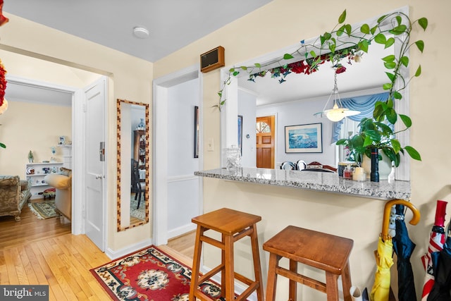 5409 20th Ave, Hyattsville, MD 20782 - kitchen with wood-type flooring, light stone counters, a kitchen breakfast bar, and baseboards