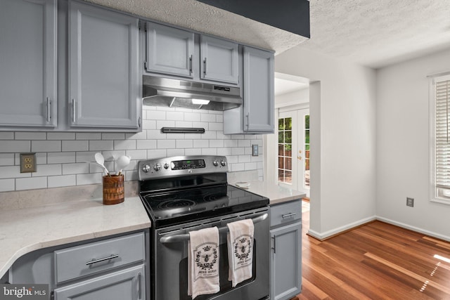 7967 Brightmeadow Ct, Ellicott City, MD 21043 - kitchen featuring stainless steel electric range oven, under cabinet range hood, gray cabinets, backsplash, and a textured ceiling