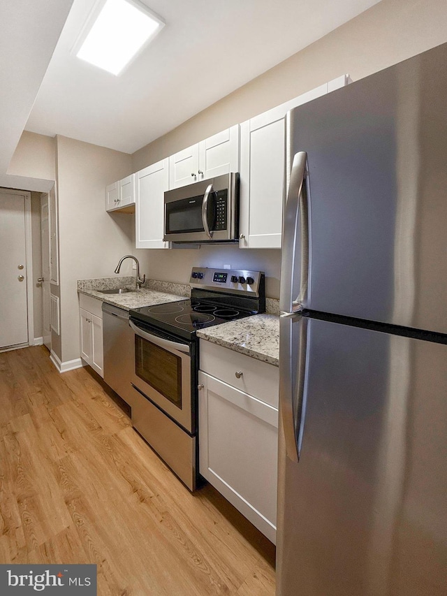 1308 Gallaudet St NE, Washington, DC 20002 - kitchen with appliances with stainless steel finishes, light wood-type flooring, white cabinetry, and light stone countertops