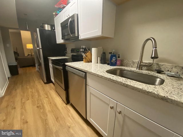 1308 Gallaudet St NE, Washington, DC 20002 - kitchen with appliances with stainless steel finishes, white cabinets, light wood-type flooring, and light stone countertops