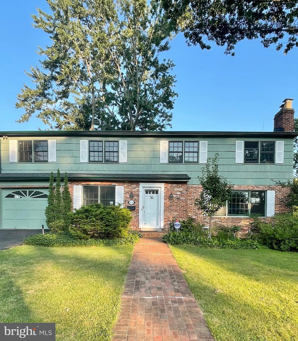 8350 Orange Ct, Alexandria, VA 22309 - view of property featuring a front lawn, a chimney, a garage, and brick siding